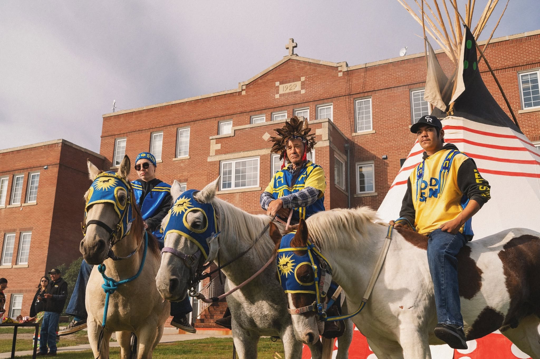 Close-up of three riders on horses with blue and gold Old Sun masks